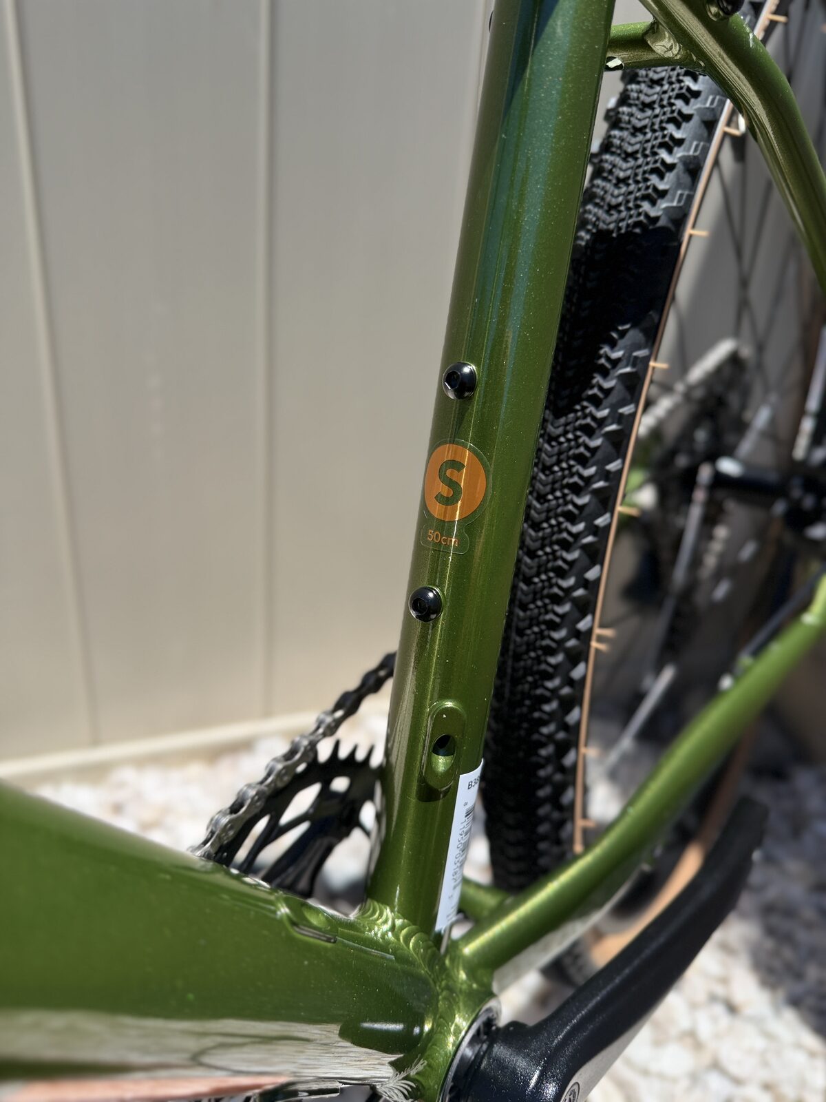 Batch GB.1 seat tube with an orange size sticker reading S / 50cm, showing rear tire clearance around the knobby gravel tire.