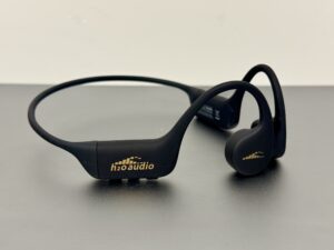 H2O Audio TRI 2 PRO Multi-Sport bone conduction headphones in the black and gold colorway, photographed on a bench.