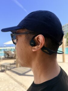 Reviewer wearing the H2O Audio TRI 2 PRO headphones walking on a pool deck before a swim session.