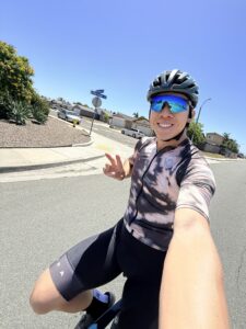 Reviewer smiling mid-ride wearing the H2O Audio TRI Run open-ear headphones under a cycling helmet.